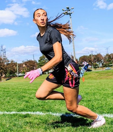 Female flag football athlete running a drill on the field in the black compression shirt