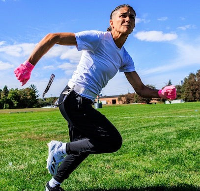 Female flag football player wearing the white compression shirt while running on the field