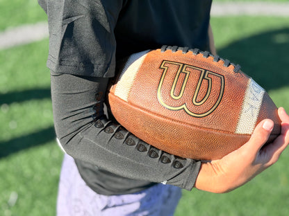 youth football player holding the ball on the grips off the compression arm sleeve