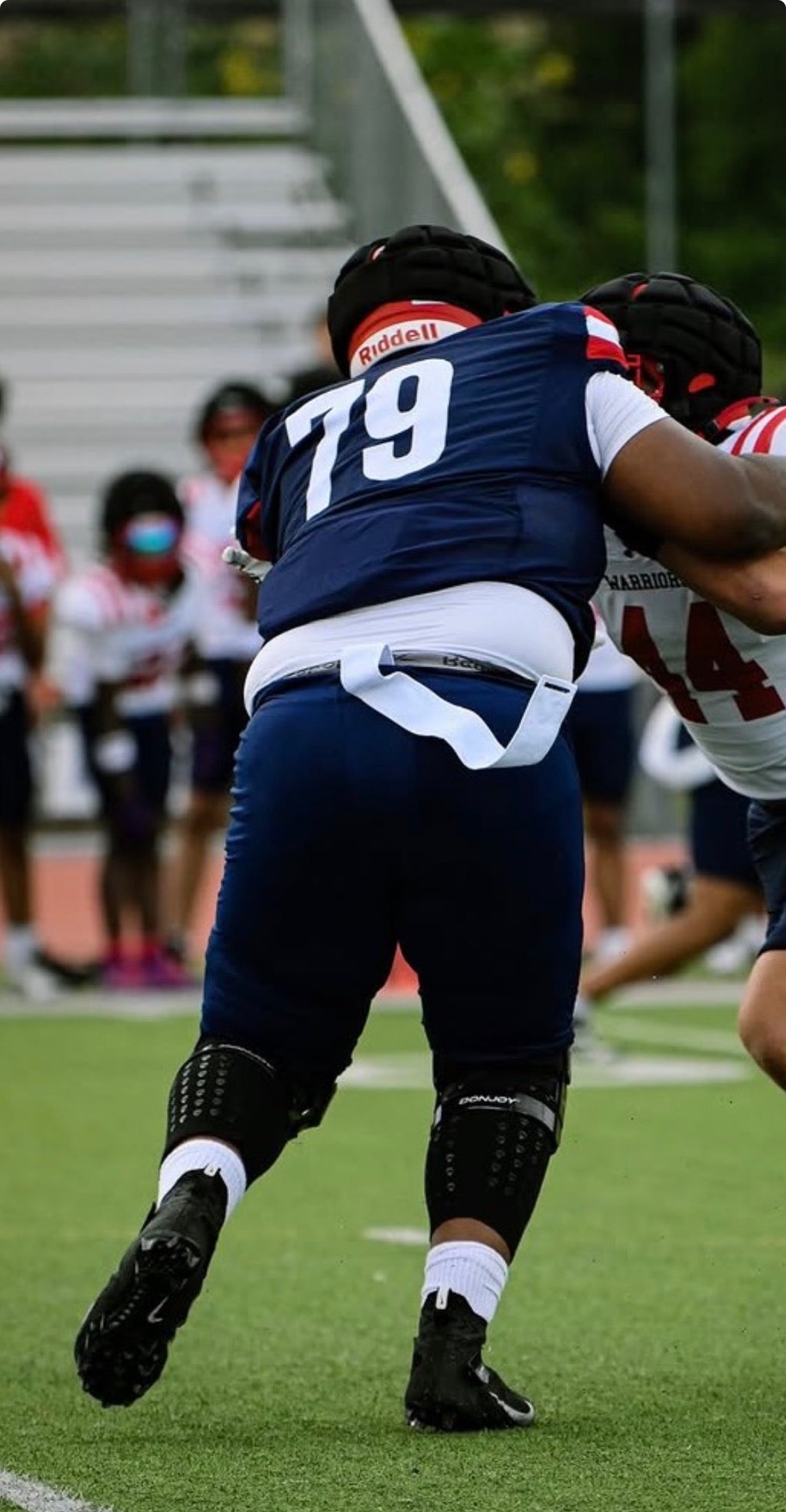 Football lineman in a blue uniform wearing black AMS Compression Leg Sleeves under his knee braces during a game